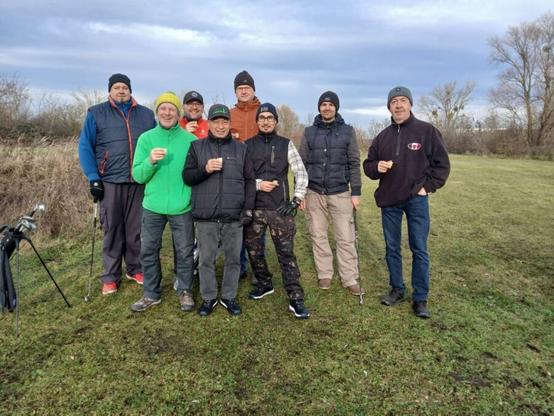 Eine Gruppe von Crossgolfern steht in Elster auf dem Crossgolfplatz und ein paar halten einen kleinen Becher Eierlikör in der hand
