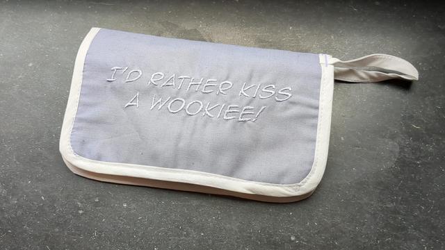Carrying case in a very muted light lavender fabric with white trim. Embroidered in the same lavender color: "I'D RATHER KISS A WOOKIEE!"