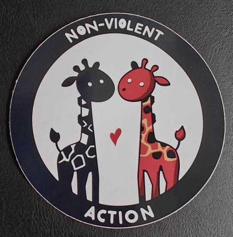 Runder Sticker mit zwei Giraffen und dem Aufdruck "Non-Violent Action"
