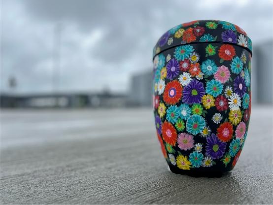 Selbstgestaltete Urne, mit bunten Blumen bemalt