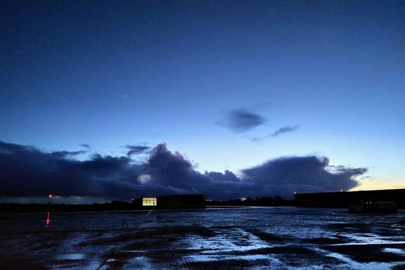 Wet apron of the JadeWeser Airport just after sunset. Heavy rain clouds are visible on the horizon under an otherwise clear sky