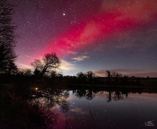 SAR arc by Paul Martin. Seen here is a red arc in the night sky with against the background of an aurora.