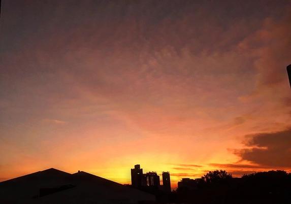 a hot looking orange sunrise with a very light clouds in the sky to show off some rays from the rising sun.