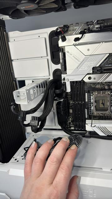 My left hand holding back three sets of webbed black power cables and connectors that were feeding into the graphics card. The CPU has been removed, as has the RAM, revealing rows of pins and capacitors beneath the CPU socket. This is but one of several reference shots I take during any major operation to make it easier for me to retrace my steps should I need to.