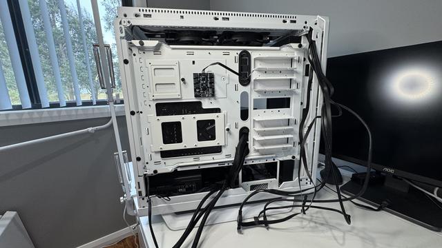 Reverse side, where before there were cable ties and tightly bound runs of straight cables, most have now been disconnected, ties cut out, and they hang freely, ready to allow me to remove the main sabot of the mainboard.