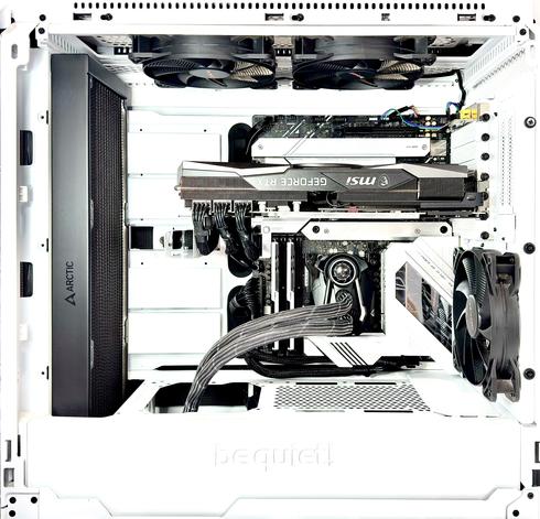 Final shot of the internals of the processor side of the case (open). The CPU cooling unit has been inverted, so now the bulbous little fan is on top of the upside-down black coffin-shaped geometric shape. The radiator hoses, in webbed grey with white stripes, look even more neat than before as they lead away below the white "deck" and the white floor paneling of the case (though one is absent, revealing a well-perforated white metal mesh below). The black radiator (left) stands tall and clean. Two black fans looking down upon the scene from above. The GEFORCE RTX card (card? more like a BLOCK of metal!) by msi is still inverted. All very high contrast and primarily white with black detail. The cabling is grouped similarly, though neater, than before. Even the few traces of colour at the edges have been tidied somewhat. It is quite a spacious case, with the motherboard taking up only two thirds of the available space. Spartan. Spacey. Dave, we are ready for boot!