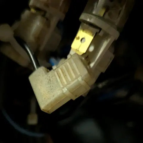 Ein auseinander gezogener Steckverbinder an einer Kontrolllampe. Der Federschuh ist mit einer Plastikkappe isoliert. Der "Fuß" an der Fassung hat ein Loch in der Mitte, in die ein Stift vom Schuh einrastet.