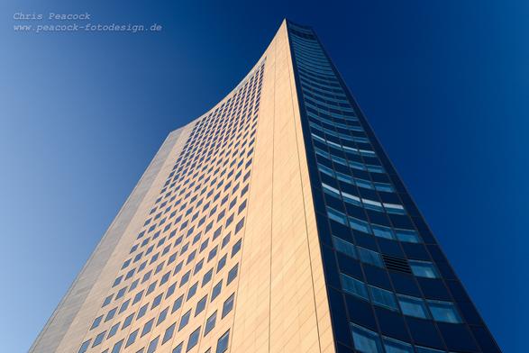 DE: Das Bild zeigt das City-Hochhaus in Leipzig in der seitlichen Ansicht. Die breitere linke Hälfte der Fassade wird von der Sonne angestrahlt. Die schmalere Stirnseite zeichnet sich eher dunkel vor dem tiefblauen Himmel ab. Der Effekt wurde durch den Polfilter verstärkt.

EN: The picture shows a side view of the City Tower in Leipzig. The wider left-hand half of the facade is illuminated by the sun. The narrower front is rather dark against the deep blue sky. The effect was enhanced by the polarising filter.