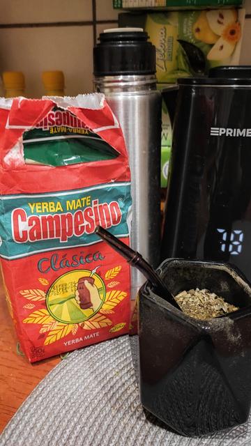 500-gramowa paczka paragwajskiej yerba mate Campesino, za nią termos, obok czarny czejnik bezprzewodowy, a przed czajnikiem czarne ceramiczne matero z fioletową bombillą, w środku pierwsze zalanie yerby..