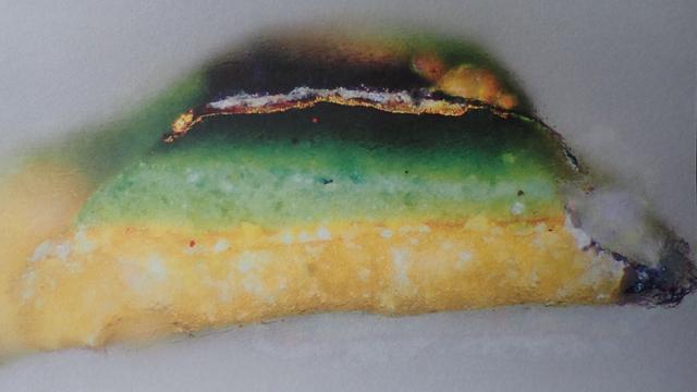Sample with a bright yellow base layer, topped by a green layer which darkens towards the top, and what looks like a glassy or burnt layer on top. From an English painting dated 1390, described as a gold leaf layer with copper glaze, depicting gilded green.