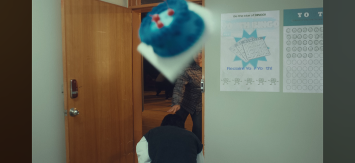 Lee Know ducks as someone throws a blue cake over his head