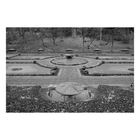 side view of an italian water garden in leafless winter with gridded canvas covers over the fountains.