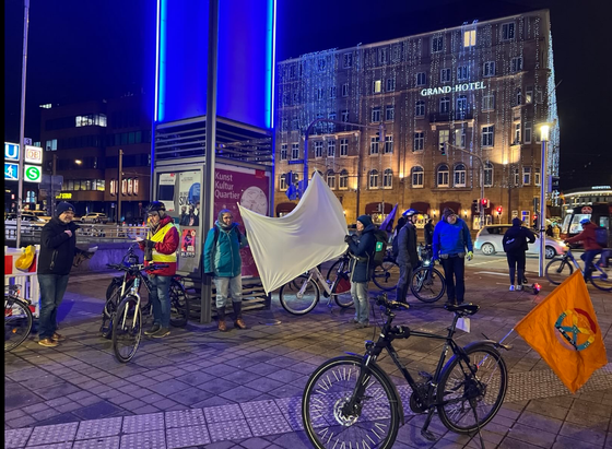 Menschen und Fahrräder mit einem weißen Leintuch gegenüber des Nürnberger Grand Hotel, das im Dunkeln mit leuchtenden "Eiszapfen"-Ketten dekoriert ist.