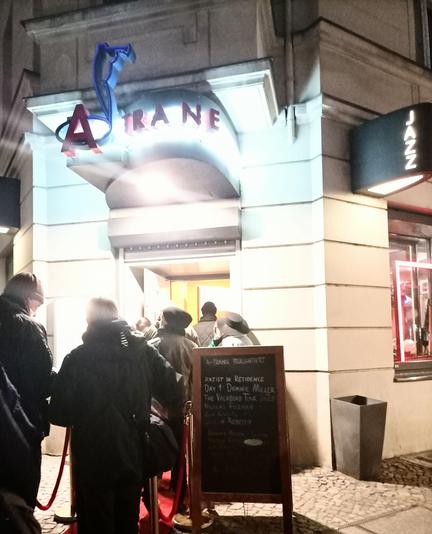 Eine Schlange vor dem Eingang des Clubs A-Trane 
Auf einer tafel ist das Konzert angekündigt