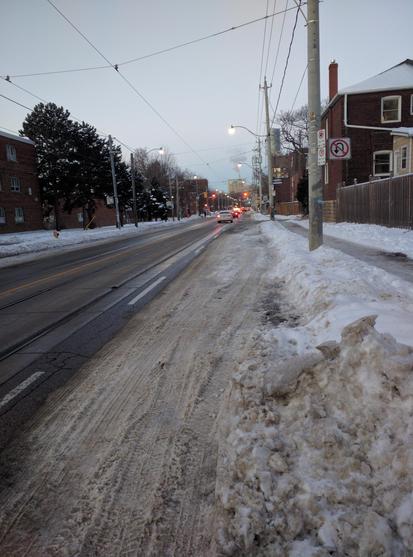 Bicycle lane nearly invisible under snow, covered in tire tracks.