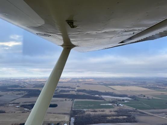 View of the wing, clouds, and ground.