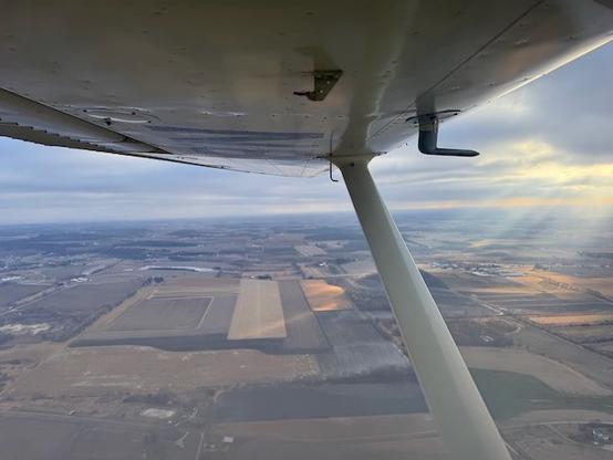 View of the wing, clouds, and ground.