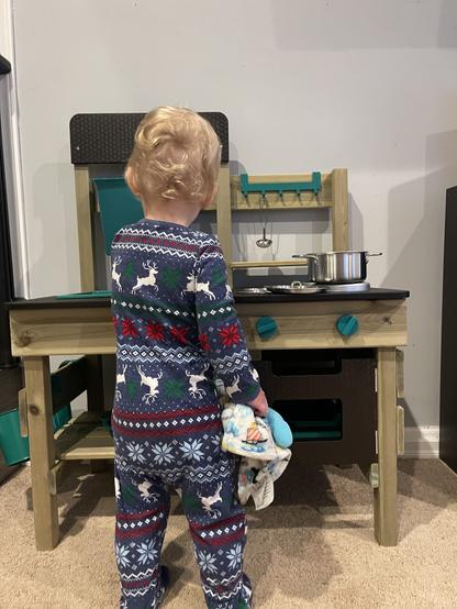 Toddler boy playing with his toy kitchen.