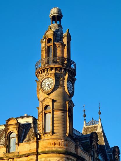 A tall, narrow circular clock tower rising above a French Renaissance style roof.
