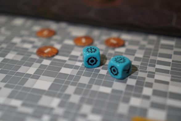 Two blue dice next to some tokens/markers from a game.