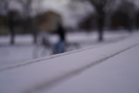 An out of focus bike in the background. Thw forground is a bench type surface covered in snow. (it's not an actual bench, but looks like one.