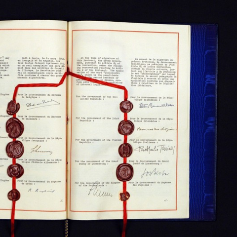 A photo of the European Convention on Human Rights, with signatures of various officials, accompanied by stamps and red ribbons as markers.