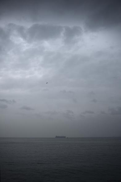a cargo ship at sea with clouds above. eyluldogruel.com