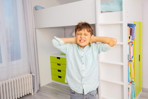 Boy overwhelmed closing eyes and hands over ears