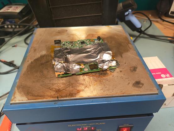 A PCB covered with kapton tape and foil tape on a electronic hotplate.