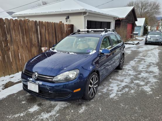 Front quarter view of a ten year old VW wagon with some snow on the ground around it.