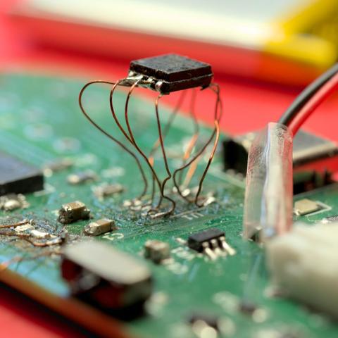 An integrated circuit is elevated above a PCB on magnet wire 'legs'. Copious blackened scorch marks are evident across the board.