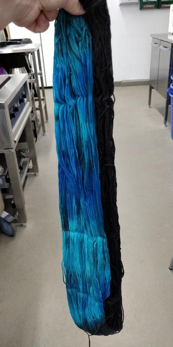 Kuiva, värjätty sinisensävyinen, lankavyyhti kädessä roikottaen.