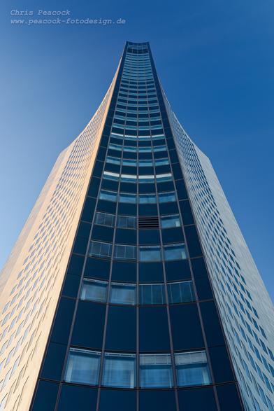 DE: Das Bild zeigt das City-Hochhaus (im Volksmund auch "Weisheitszahn" oder "Uni-Riese" genannt) in Leipzig - hier komplett aus seitlicher Ansicht. Wegen der speziellen Form wirkt es aus dieser Perspektive wie ein leicht aufgeschlagenes Buch. Es befindet sich am Augustusplatz und ist 142,5 m hoch.

EN: The picture shows the City Tower (popularly known as the "wisdom tooth" or "university giant") in Leipzig - here seen from the side. Due to its special shape, it looks like a slightly open book from this perspective. It is located on Augustusplatz and is 142.5 metres high.