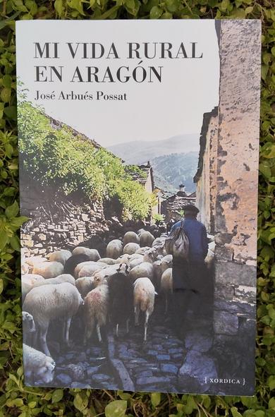 Portada del libro, un pastor avanza con sus ovejas en la calle de un pueblo altoaragonés, editorial Xordica