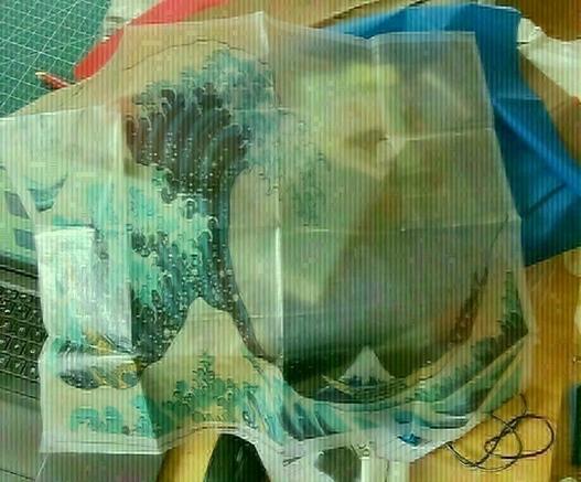 Hokusai's great wave printed on dcf 1.0, lots of transparency on the white parts. it's a rectangular shape, around 40*50cm, and we can see where it was folded. mess in the background