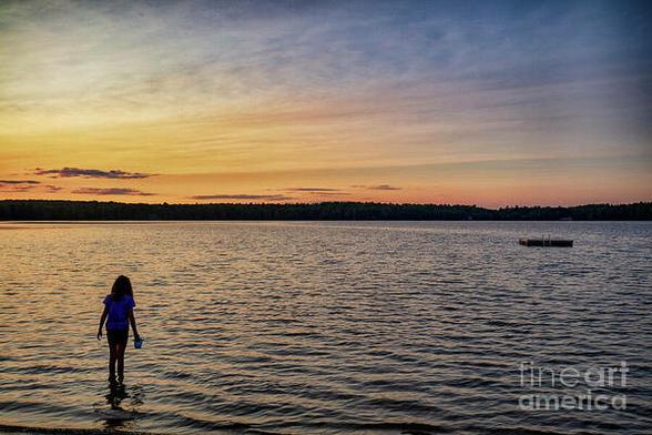 Daylight to Evening is a color photograph taken at sunset at Twin Lakes in Shohola PA of a little girl enjoying the water with her pail and shovel.