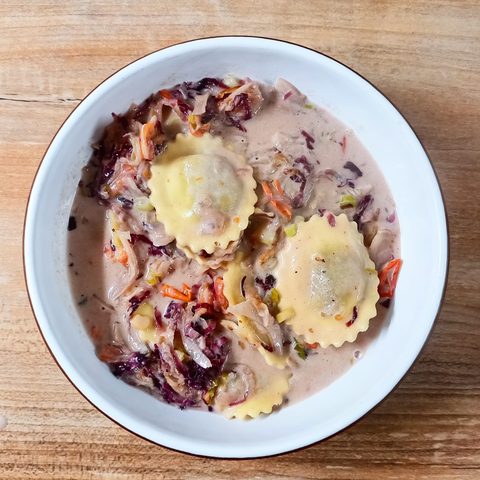 Eine Schale mit heller Sauce, darin die genannten klein geschnittenen Gemüse und einige Ravioli