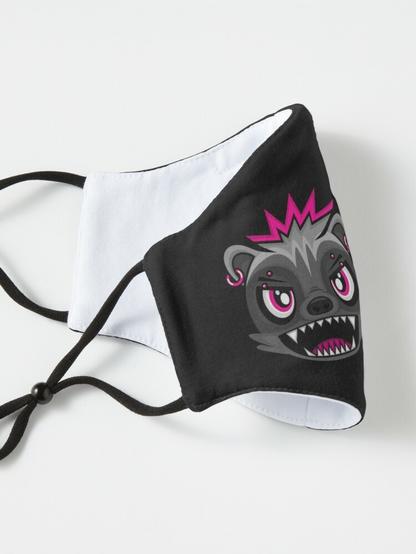 Picture of HUNNY BADJA's face on a black mask. She's got an angry expression, looking towards the viewer with her pierced eyebrows at a scornful angle, her mouth wide open with her sharp teeth bared, spiky hair with pink tips, and pink earrings.