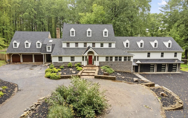 A house that is very wide with 5 different types of garage doors, some are a similar style but different widths, and some are a modern style compared to the others which are traditional