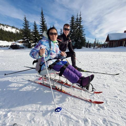 Me with my ski poles on a Nordic sitski on the mountain & 1 instructor