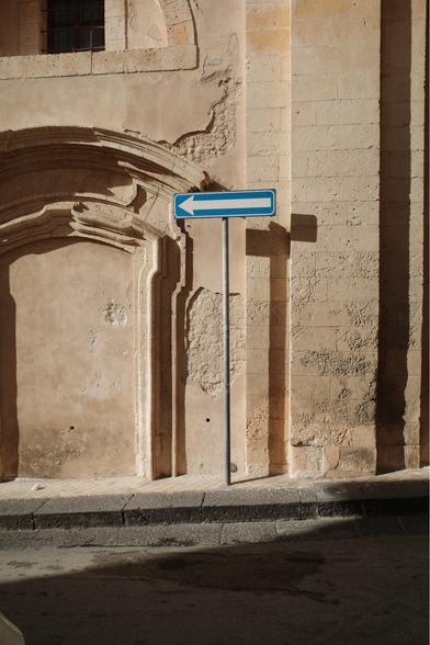 Shadows against a wall with a street sign