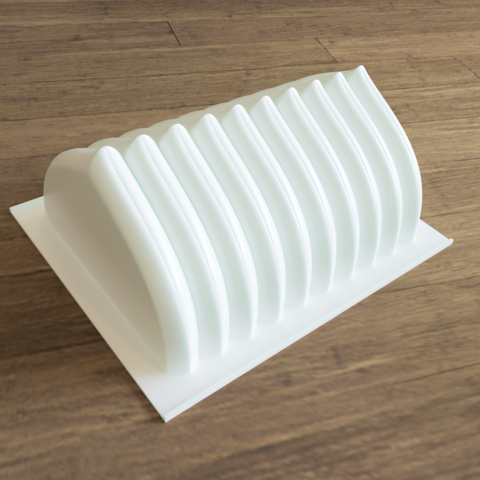 Moule de bûche de Noël en PLA. Le moule fait environ 20cm de long pour 15 de large. Elle est constituée d'arc en accolade répétés 10 fois dans la longueur, le tout sur une plaque rectangulaire.