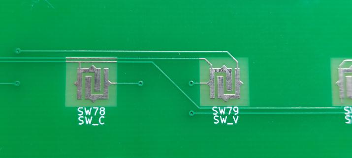 Two square footprints for key switches. Unlike other pads, these consist of two J shapes hooked into each other. The sides feature triangle shapes where the original traces would be connected.