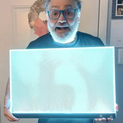 A man (me) holding a light pad which is large enough to draw comic book pages.