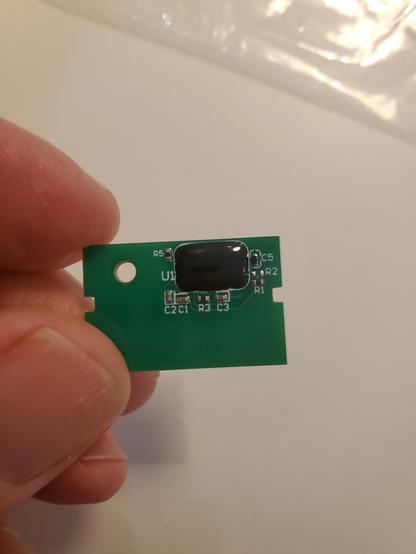 A replacement toner chip held between finger and thumb