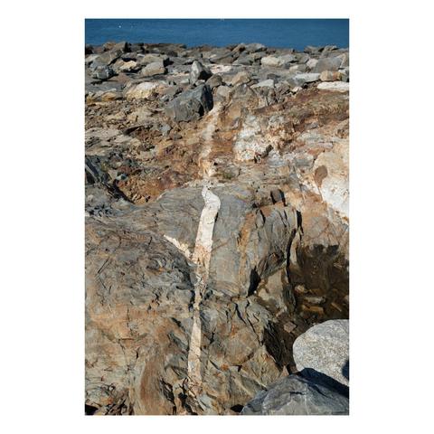 an entirely rocky ocean shore with a white vein separating rocks