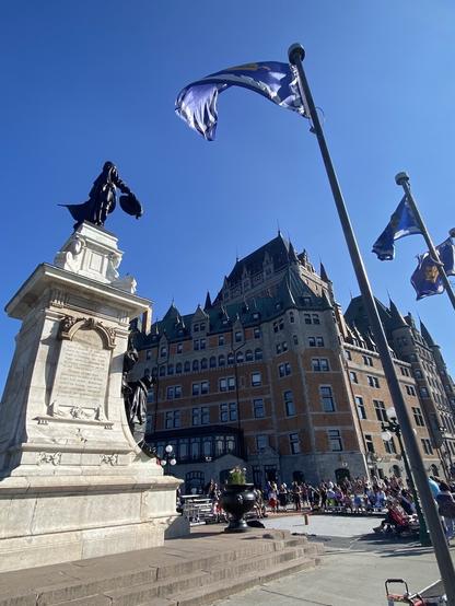 A flag snaps in the breeze next to a statue in Quebec