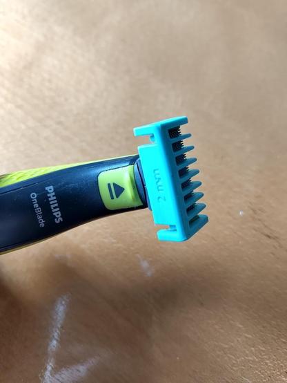 Teal colored comb on a Philips One Blade device.