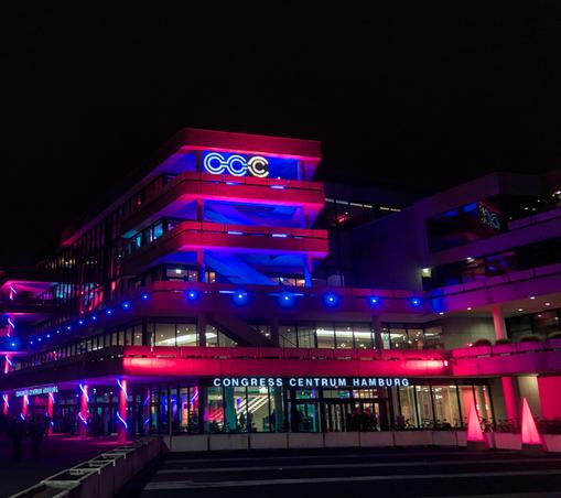 The old CCH building at night, with ared and blue lighting. The CCH logo has been modified to say "CCC".