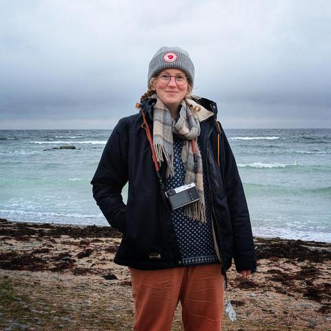 Gemma standing on the beach wrapped up for winter. The weather is cool and bleak.